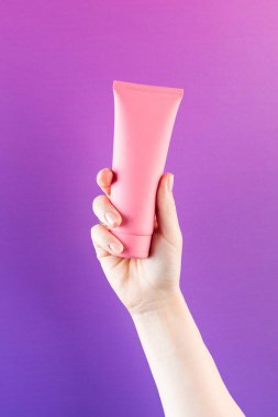  Mor arka planda kozmetik ürünü olan pembe bir tüp. Boşluğu kopyala. 