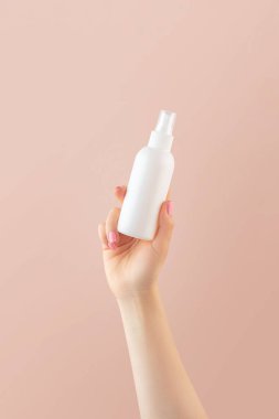 Bayan el fıskiyesi açık pembe arka planda şişeden hava tazeleyici sprey sıkar. Atmosfer için doğal deodorant. Metin için boşluk