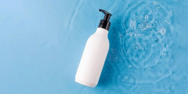 Yukarıdan mavi arkaplan manzaralı, su dolu boş bir şişe. Yeniden kullanılabilir pakette kozmetik ürünler. Çevre dostu ve geri dönüşümlü konteynır