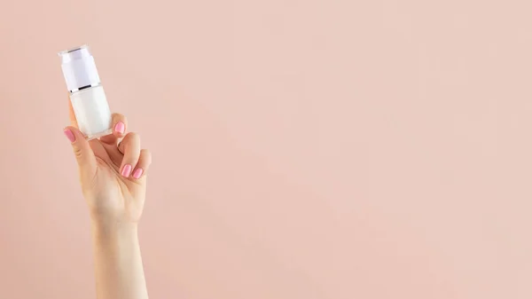 A mock-up of a jar of moisturizer in a womans hand on a pink background. Copy space.