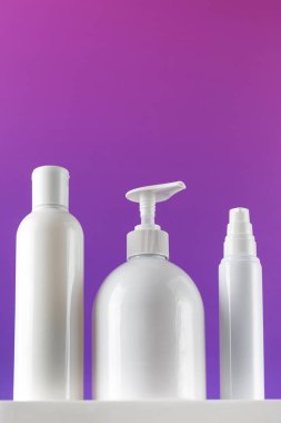  Mor bir arka planda kaidede kozmetik ürünleri olan beyaz konteynırların maketleri. Cilt bakımı, kozmetik mağazası konsepti.