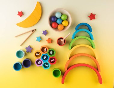 Sarı arka planda, okul öncesi çocuklar için Montessori metoduna göre çevre dostu ahşap eğitim oyuncakları. Tahta gökkuşağı ve diğer oyuncaklar.