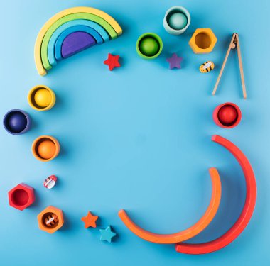 Ahşap eğitici oyuncaklardan yapılmış çerçeve mavi arka planda metin için yeri var. Uzayı kopyala Erken çocukluk gelişimi kavramı.