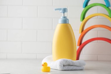 Bebek ve çocuk cilt bakımı için kozmetik ürünleri olan sarı bir şeker kutusu ve ahşap gökkuşağı arka planında küçük bir ördek. Boşluğu kopyala