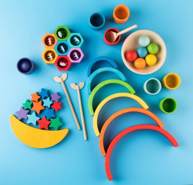 Mavi arka planda, okul öncesi çocuklar için Montessori metoduna göre çevre dostu ahşap eğitim oyuncakları. Tahta gökkuşağı, denge ışını ve diğer oyuncaklar.