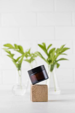 Kahverengi cam kozmetik kavanozu ahşap bir podyumun üzerinde havalanır. Günlük kullanım için deri ve vücut losyonu. Logo için şablon