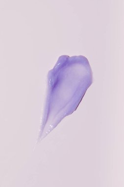 Pembe arka planda mor bir kozmetik lekesi. Reklam için bir örnek, cilt bakımı konsepti..