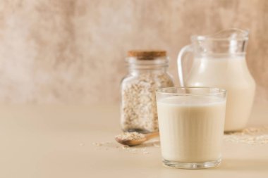 Bir bardak yulaf sütü, bir sürahi ve yulaf ezmesi. Alternatif laktozsuz süt ürünleri kavramı. Sağlıklı yaşam tarzı