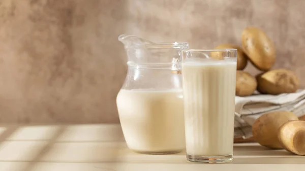 ボウルに生のジャガイモとジャガイモミルクのガラスとジャグ 牛乳代用品 ベジタリアン用牛乳 — ストック写真