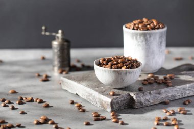 Gri tahtadaki bir kasede kavrulmuş kahve çekirdekleri. Kahve arka planı.