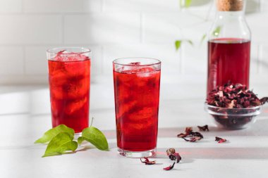 Kurumuş amber yaprağından yapılmış ferahlatıcı bir içecek ve gölgeli açık arkaplanlı bir fincanda buz. Karkade çayı tazeleniyor.