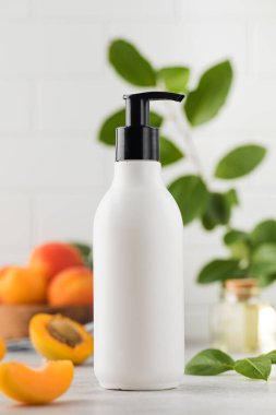  Kayısı çekirdeği özüyle birlikte kozmetik sıvı ürün içeren beyaz bir dağıtıcının maketi. Rutin vücut ve saç bakımı için kozmetik ürün.