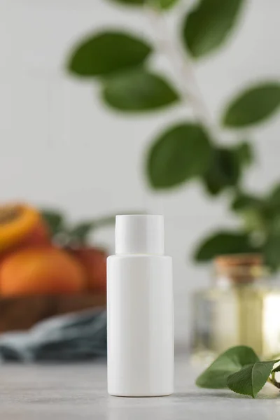 Mockup of a white tube of cosmetics with apricot kernel extract among leaves and fresh fruits. The concept of natural plant cosmetics. Layout.