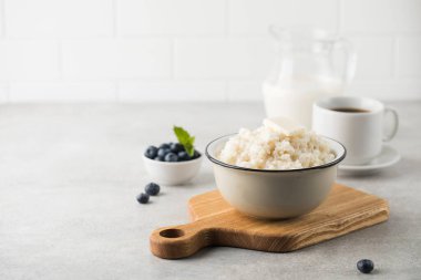 Pirinç lapası veya bir parça tereyağlı puding, gri bir masada bir kase kahve ve yabanmersini. Sağlıklı kahvaltı. Boşluğu kopyala