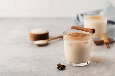Ev yapımı Horchata pirinç, gri beton arka planda buzlu ve tarçın çubuklu bir bardakta içilir. Vejetaryen meşrubatı, ulusal mutfak. Boşluğu kopyala.