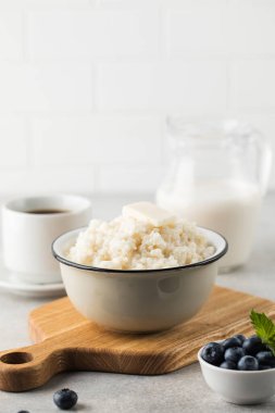 Pirinç lapası veya bir parça tereyağlı puding, gri bir masada bir kase kahve ve yabanmersini. Sağlıklı kahvaltı..