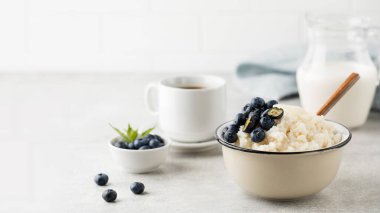 Bir kase dolusu kahve ve masada bir sürahi sütle yaban mersinli sütlü puding. Sağlıklı glütensiz kahvaltı tarifi. Boşluğu kopyala.