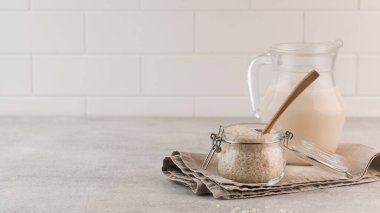 Hafif bir arka planda bir kavanoz kuru pirinç ve bir sürahi pirinç sütü. Sağlıklı gıda konsepti, alternatif süt.. 