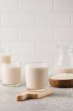 Bir bardak sebzeli pirinç sütü ve gri arka planda bir sürahi. Vejetaryen yemeği, laktozsuz süt. Sağlıklı yaşam tarzı.