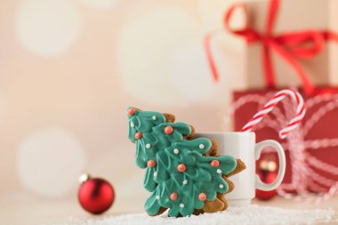 Noel ağacı şeklinde zencefilli çörek, çizgili lolipoplu bir fincan ve hediyeler ve bokeh.