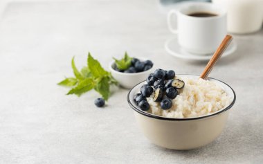 Yaban mersinli sütlü pirinç lapası ve bir kupa sade kahve. Sağlıklı ve lezzetli kahvaltı kavramı. Boşluğu kopyala
