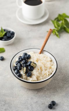 Yaban mersinli sütlü pirinç lapası ve bir kupa sade kahve. Sağlıklı ve lezzetli kahvaltı konsepti.