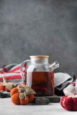 Gri zemin üzerinde siyah çay ve örülmüş balkabakları olan cam çaydanlık. Sonbahar ve samimiyet kavramı. Sonbahar çayı..