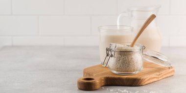  Bir kavanoz çiğ pirinç ve pirinç sütü gri arka planda bir kalas üzerinde bir bardakta. Sağlıklı gıda kavramı, alternatif süt. Boşluğu kopyala