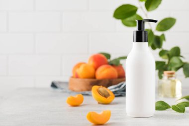  Kayısı çekirdeği özüyle birlikte kozmetik sıvı ürün içeren beyaz bir dağıtıcının maketi. Rutin vücut ve saç bakımı için kozmetik ürünler. Boşluğu kopyala