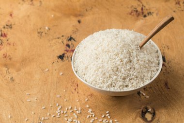 Tahta bir arka planda yakın plan kasede çiğ beyaz pirinç. Vejetaryen yemeği. Sağlıklı yiyecekler. Boşluğu kopyala