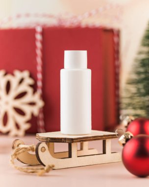 Noel arkaplanında beyaz bir şişenin kışın cilt bakımı kozmetik ürünüyle kopyası. Noel için kozmetik hediye konsepti, yeni yıl kozmetik reklamı.