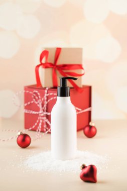 Karda kozmetik ürünü olan beyaz bir kutunun maketi Noel hediyelerinin arka planında. Yeni yıl hediyeleri.