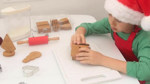 Uma Criança Chapéu Claus Está Fazer Uma Casa Gengibre Cozinha — Vídeo de Stock