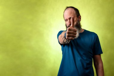 Sıradan kıyafetler giymiş orta yaşlı bir adam başparmağını kaldırıyor, başarı ve onay işareti, seçici odaklanma..