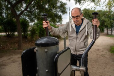Adam halka açık bir parkta kros kayak makinesiyle egzersiz yapıyor..