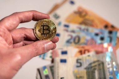 Avro banknotlarının arka planında Bitcoin para tutuyor. Bitcoin kripto para birimi yatırım kavramı.