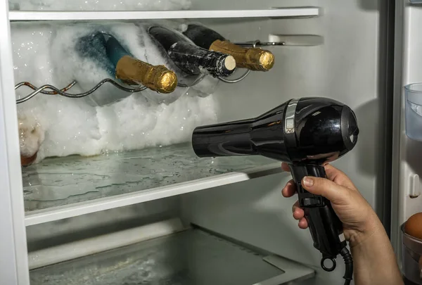 헤어드라이어를 사용하여 냉장고에서 얼음을 튀기는 모습. 로열티 프리 스톡 이미지