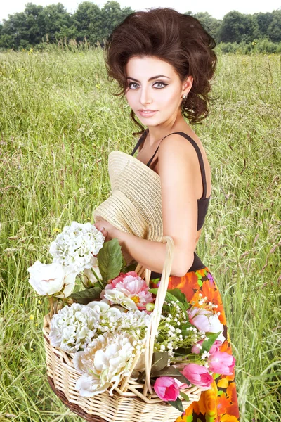 Hermosa mujer con flores en el campo —  Fotos de Stock