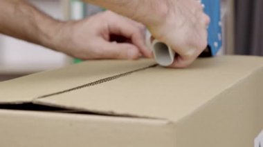 Genç bir erkek mağaza sahibi, depo çalışanı, kaset paketli tüccar fişleri teslimat karton kutu hazırlıyor. Eller yukarı. Posta servisi. Yavaş çekim hazır 59.94fps.