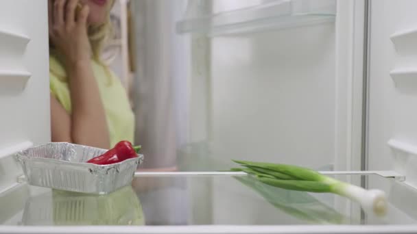 İnternetten alışveriş teslimatı. Kadın yemek aramak için buzdolabını açıyor ve beslenme almak için modern çevrimiçi gıda dükkanı servisini kullanıyor. Buzdolabının içinden bak. Kapatın. Yavaş çekim hazır 59.94fps. — Stok video