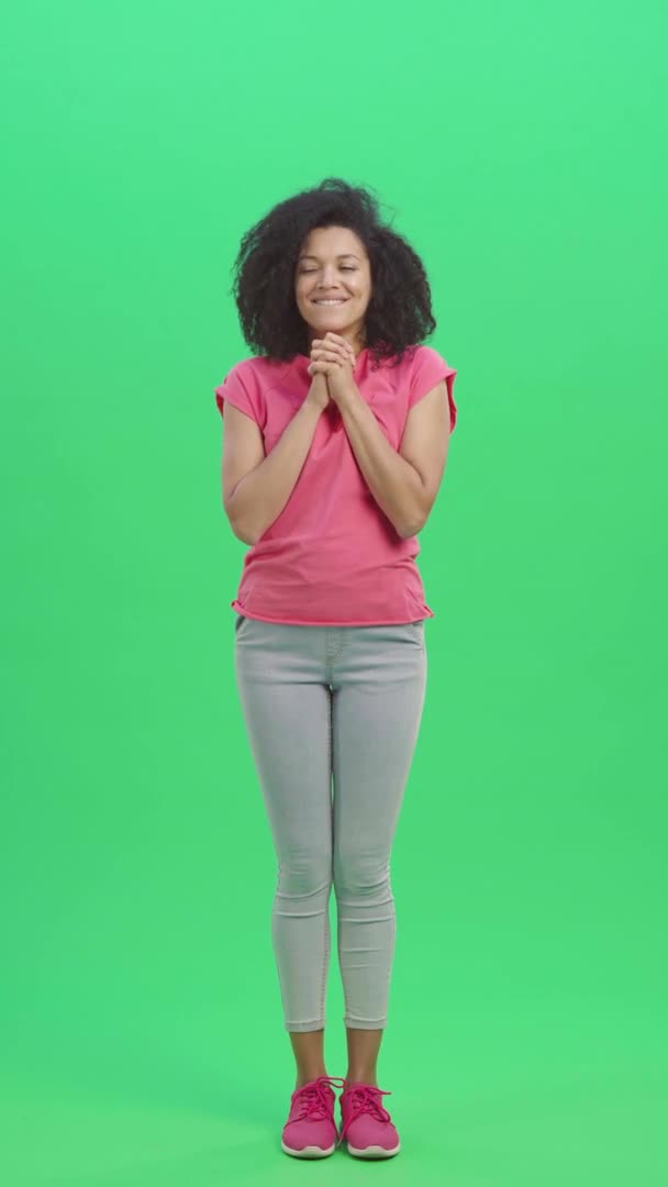 Портрет молодої щасливої афроамериканки мріє про щось приємне. Чорна жінка з хвилястим волоссям на зеленому екрані в студії. Повільний рух готовий до 59.97fps.Вертикальне відео. Повна довжина. — стокове відео