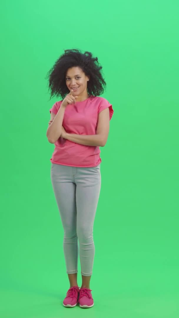 Porträtt av unga kvinnliga afroamerikanska coquettishly tittar på kameran och gester ringa mig. Svart kvinna med lockigt hår poserar på grön skärm. Slow motion klar 59,97fps. fp. Full längd. — Stockvideo