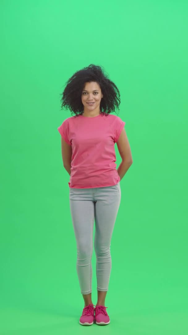 Portrait of young female African American nods head and points not to do it with a gesture. Black woman with curly hair poses on green screen. Slow motion ready 59.97fps. Vertical video. Full length. — Stock Video