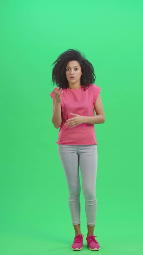 Портрет молодой женщины-афроамериканки испуганно смотрит в камеру и говорит: Боже мой. Черная женщина с вьющимися волосами позирует на зеленом экране. Slow motion ready 59.97fps. Вертикальное видео. Полная длина. — стоковое видео