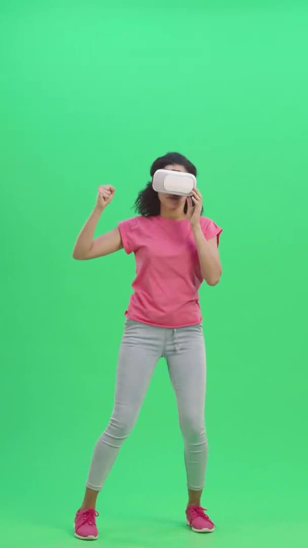 Portrait de jeune Afro-Américaine avec casque de réalité virtuelle ou lunettes 3D. Femme noire aux cheveux bouclés pose sur écran vert. Prêt au ralenti 59,97 pi. Vidéo verticale. Longueur totale. — Video