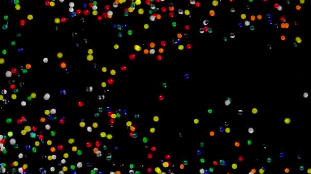 Muchas bolas de gel de agua multicolor se mueven abstractamente a través de la pantalla sobre un fondo negro. Bolas de hidrogel orbeez rebotando y volar en diferentes direcciones. Gel superabsorbente de polímero. De cerca. — Vídeo de stock