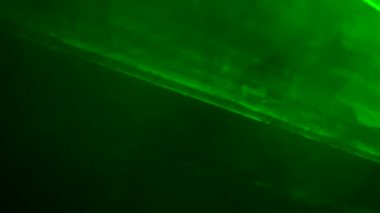 Parlak yeşil neon ışıklı ışıklar yanıp sönüyor ve dumanlı karanlık bir stüdyoda ışık saçıyor. Sahne ışıkları. Aydınlatma, aydınlatma, sahnede tiyatro dumanı. Tatil, gece kulübü, disko, parti. Kapat..