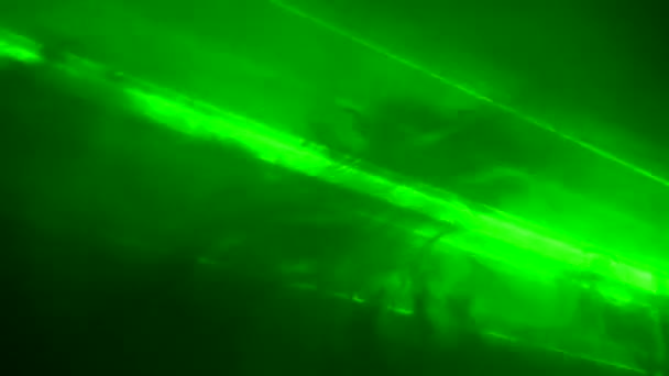Feixes brilhantes de luz laser de néon verde pisca e emite luzes em um estúdio escuro esfumaçado. Luzes de palco. Iluminação, iluminação, fumaça teatral no palco. Férias, discoteca, discoteca, festa. Fechar. — Vídeo de Stock