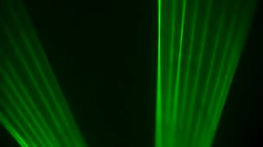 Siyah stüdyo arka planında renkli yeşil neon lazer ışıkları dumanlar içinde dönüyor. Lazer hologramlar döner ve ışık yayar. Tasarım için ışık efektleri, sahne aydınlatma, gösteri, disko. Kapat..