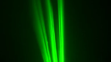 Siyah stüdyo arka planında renkli yeşil neon lazer ışıkları dumanlar içinde dönüyor. Lazer hologramlar döner ve ışık yayar. Tasarım için ışık efektleri, sahne aydınlatma, gösteri, disko. Kapat..